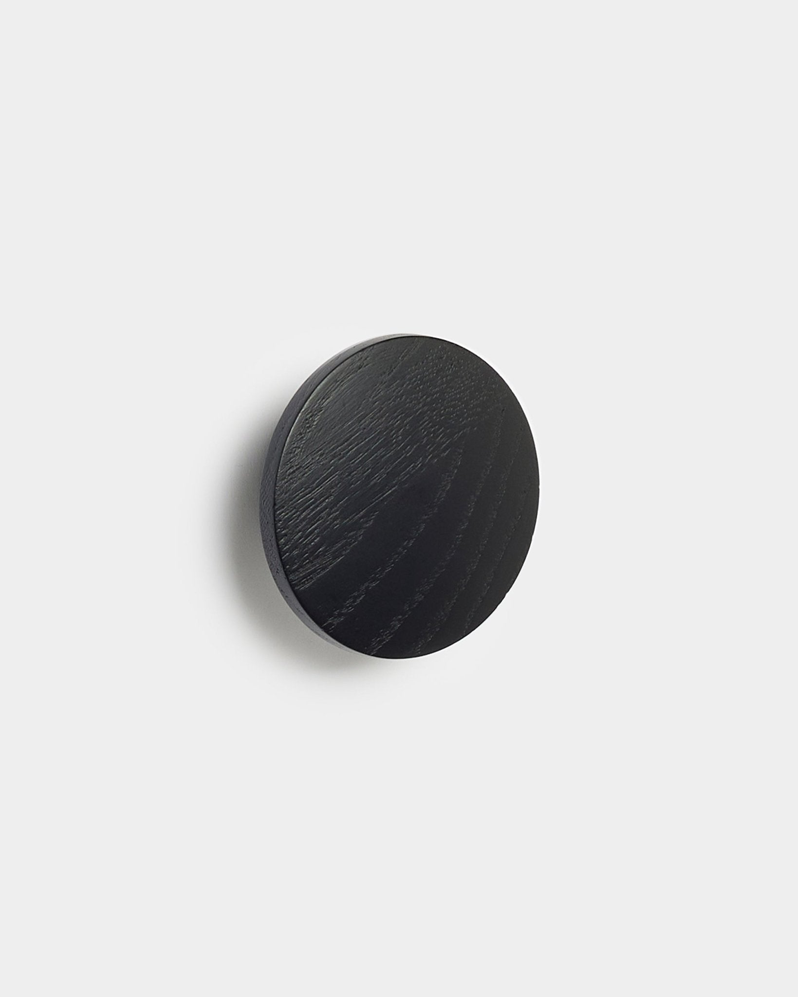 The Linn | Single Hanger in black oak by WoodUpp, a round accessory for Akupanel acoustic panels, displayed against a plain white background.